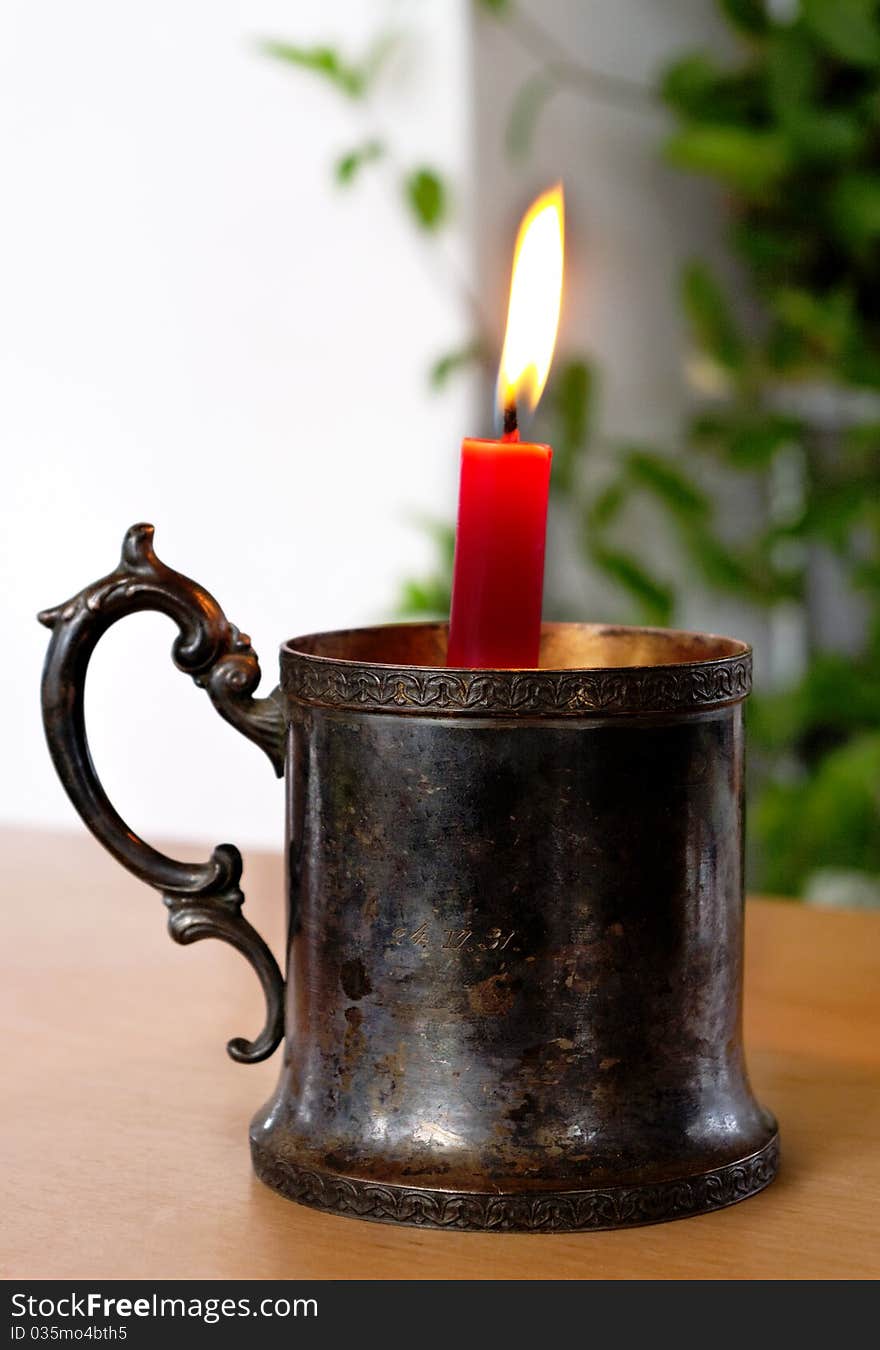 Candlestick with flaming candle on the table. Candlestick with flaming candle on the table.