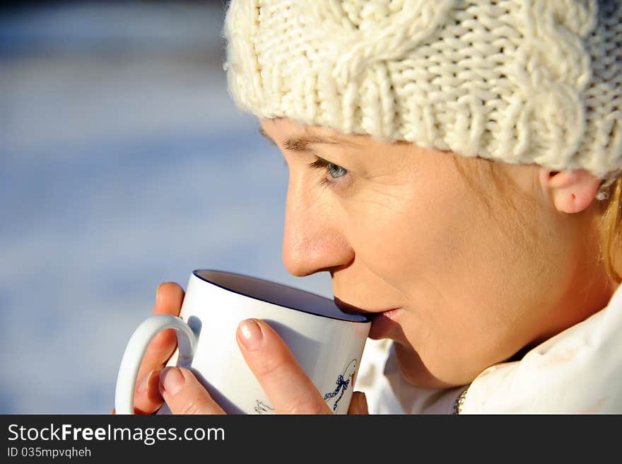 Portrait of adult woman in white, with mug in his hands, bright sunny frosty day