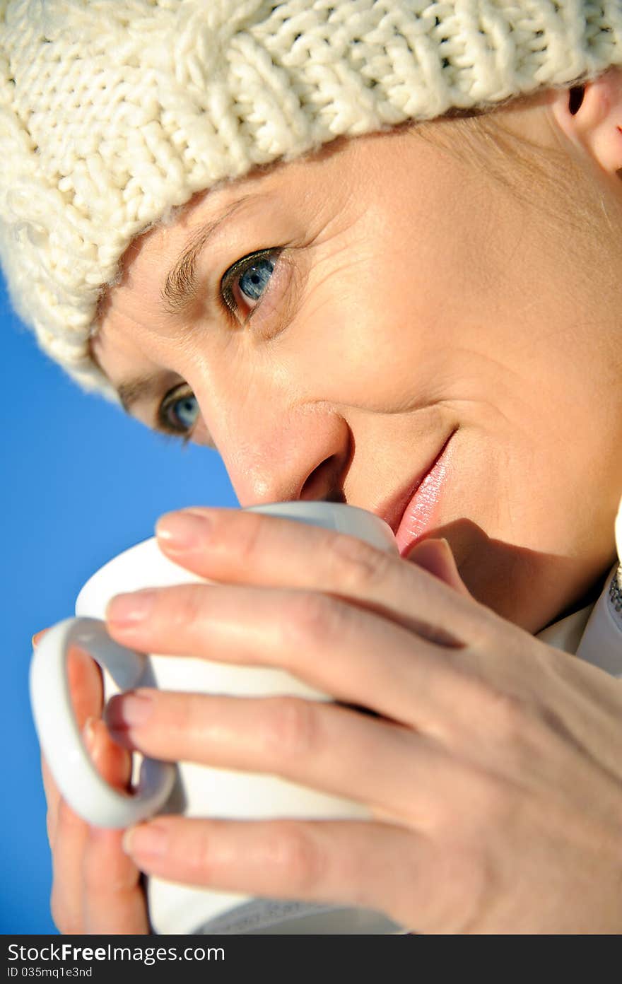 Portrait of adult woman in white, with mug in his hands, bright sunny frosty day