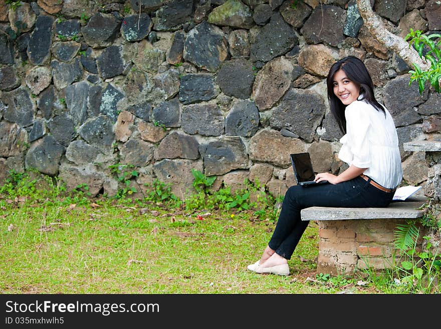 A happy female college student is working in university's park. A happy female college student is working in university's park