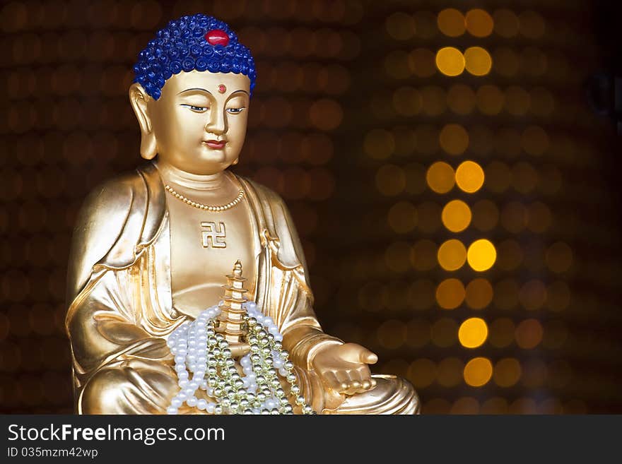 A golden Buddha statue with twinkling light in the background