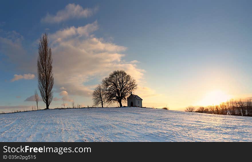 Sunset on frozen field with a chapel