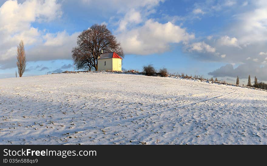 Frozen field with a chapel and clouds