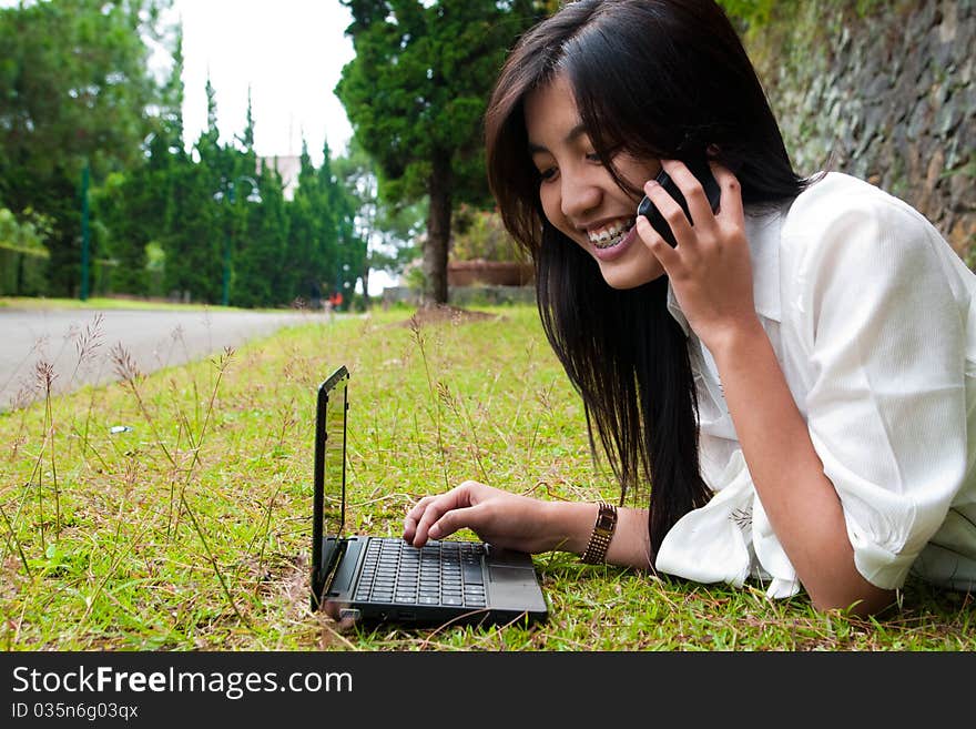 A happy female college student is working in university's park. A happy female college student is working in university's park