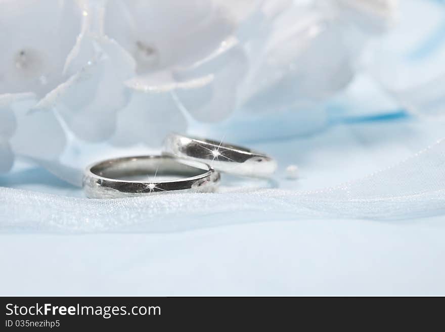 White flowers from a wedding on blue background with blue and white ribbon and two rings. White flowers from a wedding on blue background with blue and white ribbon and two rings