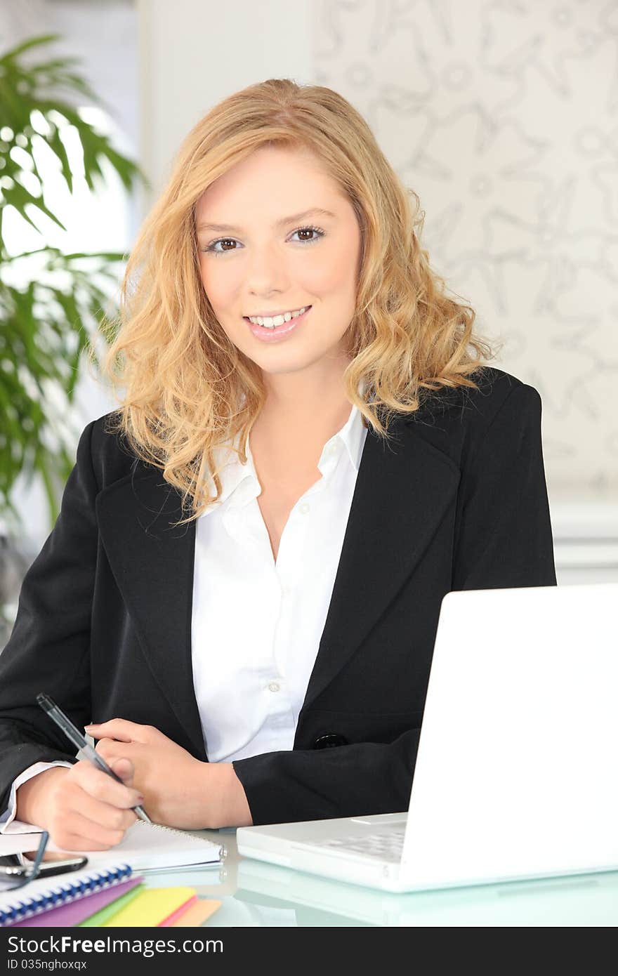 Young woman smiling sitting at a desk. Young woman smiling sitting at a desk