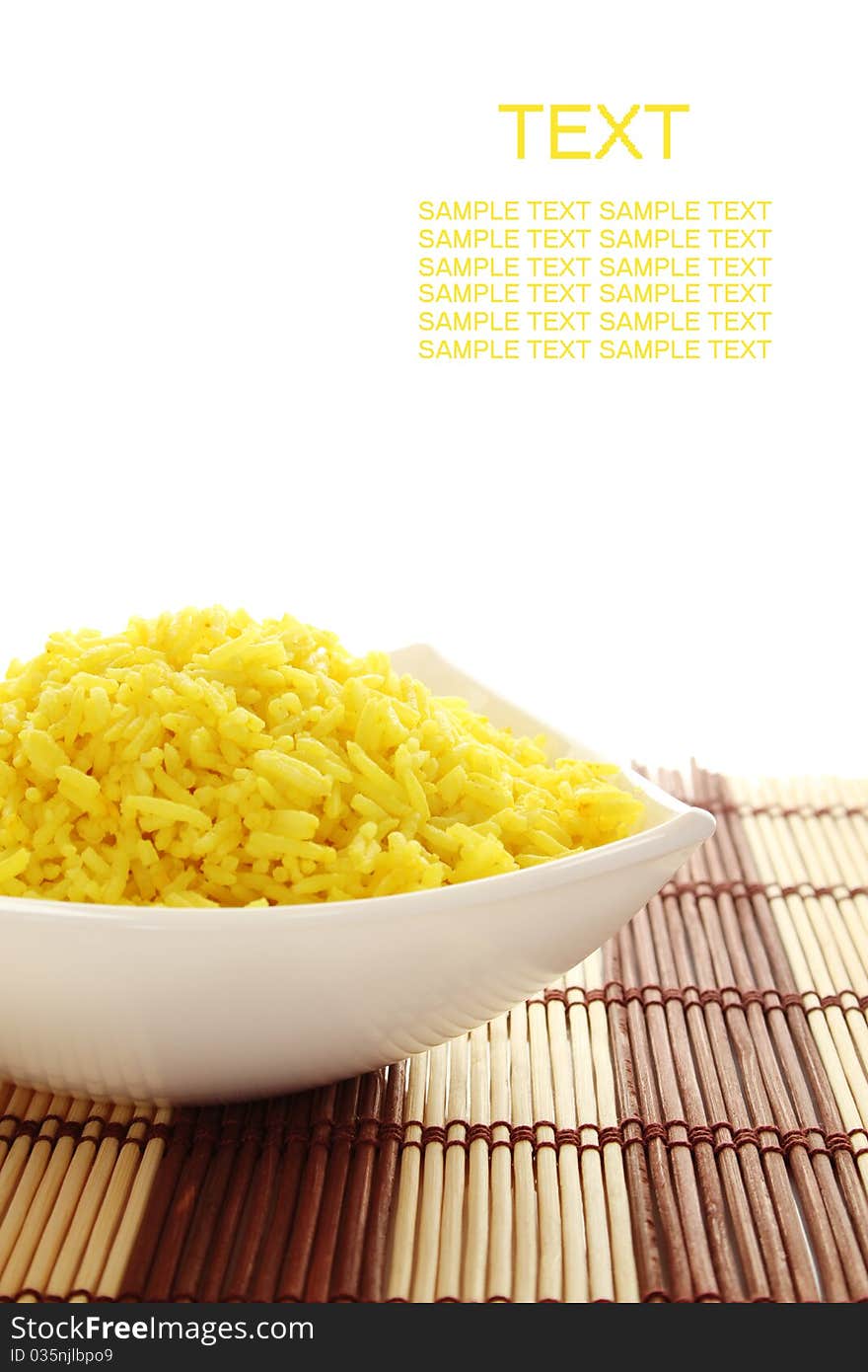 Boiled yellow rice boiled in white bowl. Plate stands on a wooden mat. Isolated on a white background. Boiled yellow rice boiled in white bowl. Plate stands on a wooden mat. Isolated on a white background