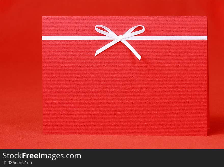 Red invitation card with bow on red silk satin background