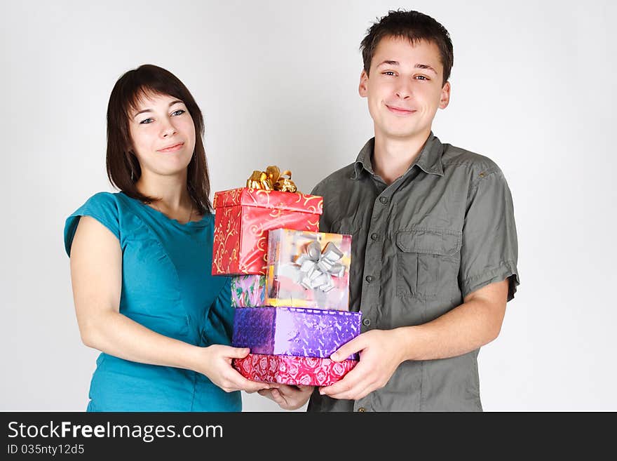 Young happy brunette man and girl holding many gifts and smiling. Young happy brunette man and girl holding many gifts and smiling