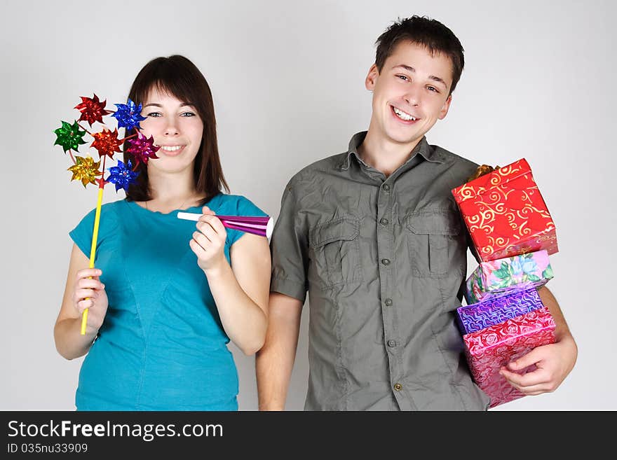 Young happy brunette man and girl holding many gifts and other party items and smiling. Young happy brunette man and girl holding many gifts and other party items and smiling