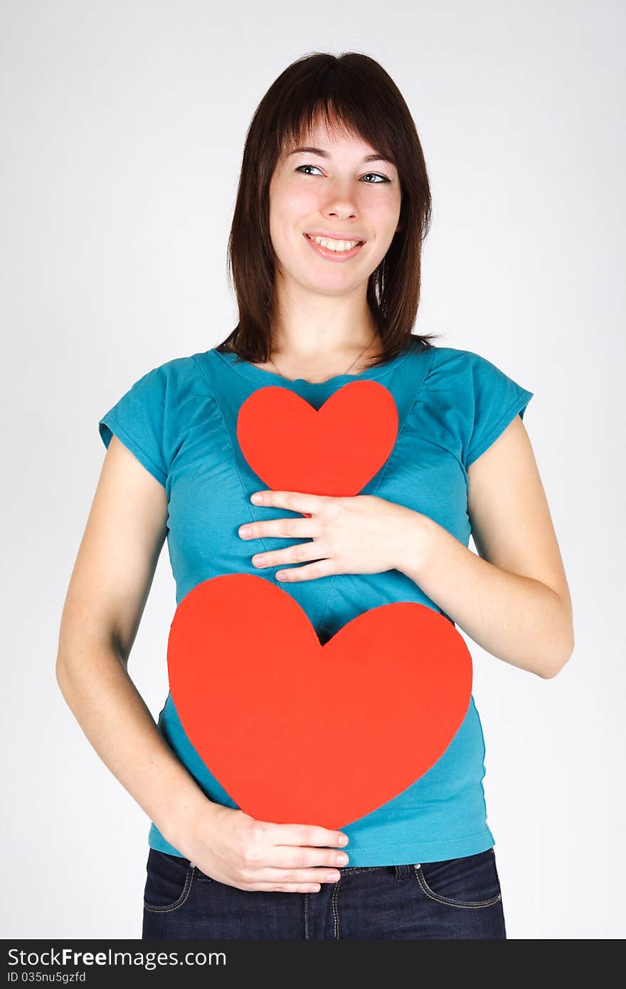 Young beauty girl holding two paper hearts, smiling and looking at side