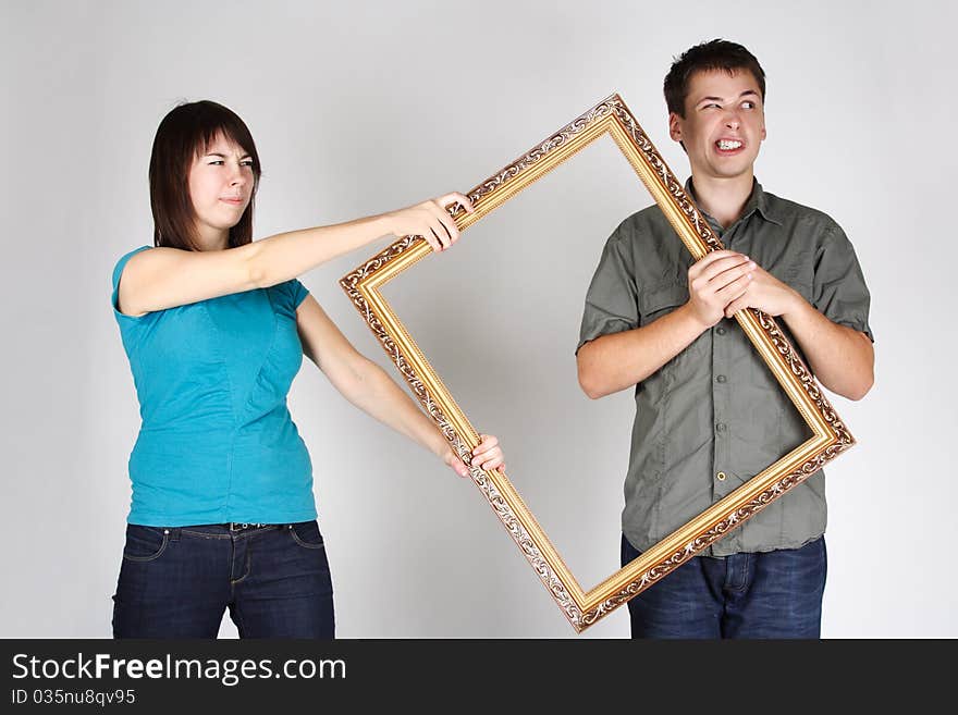 Woman wresting gold decorative frame from man, angry faces. Woman wresting gold decorative frame from man, angry faces