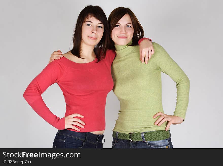 Two young brunette girls in red and green shirts embracing. Two young brunette girls in red and green shirts embracing