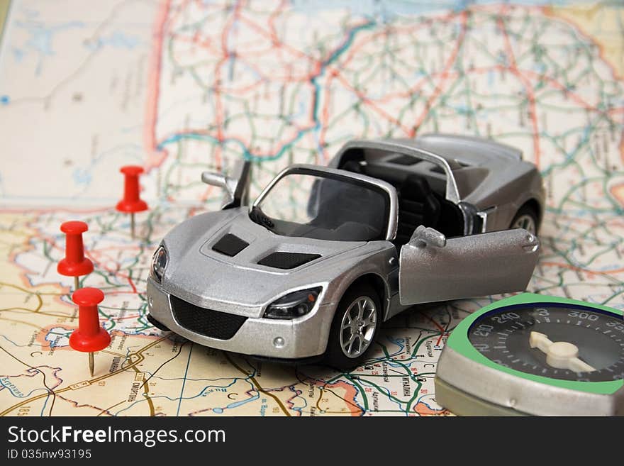 A toy car is on the road map. convertible silver. A toy car is on the road map. convertible silver