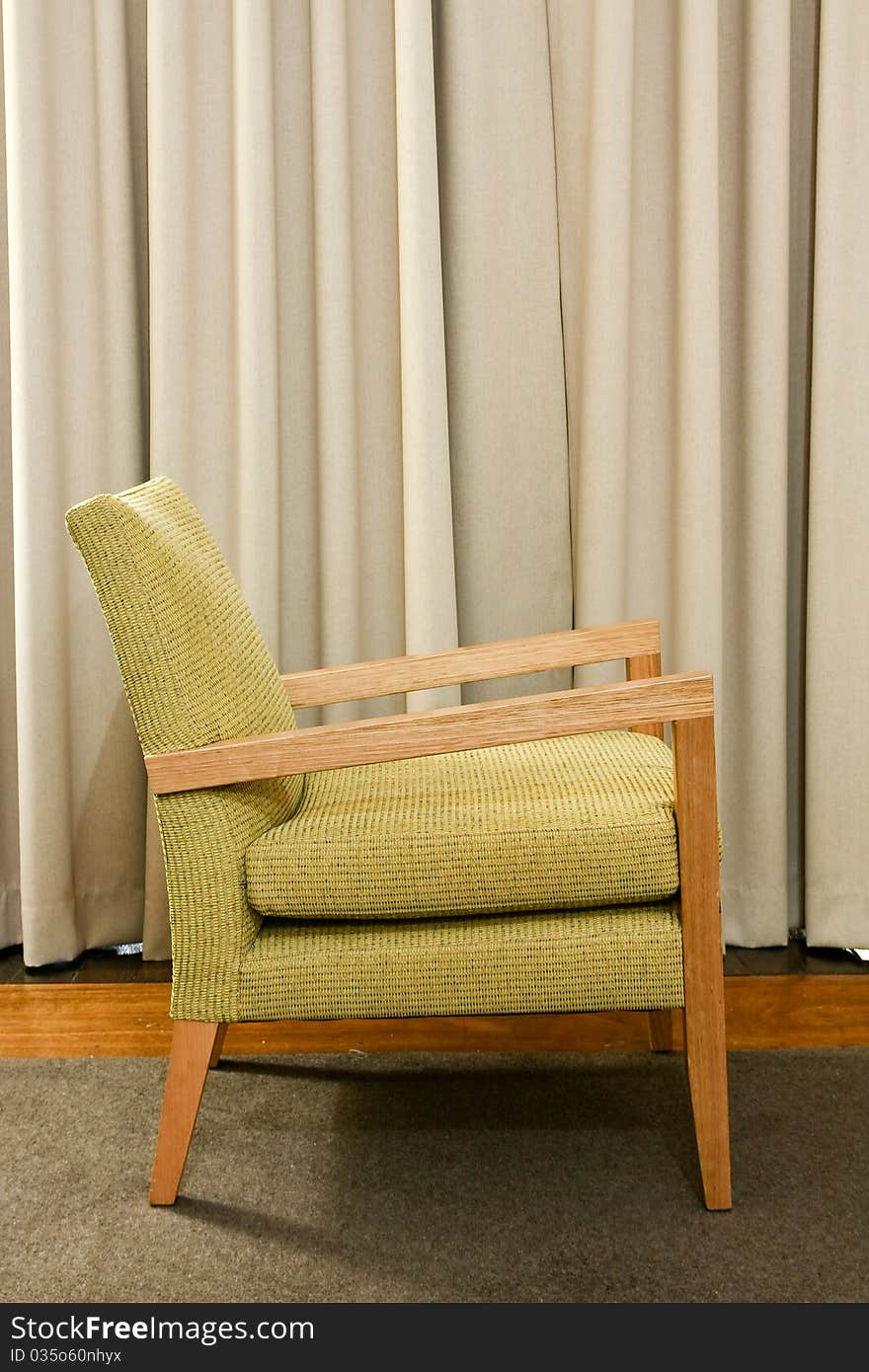 Green wooden and upholstered chair on rug.