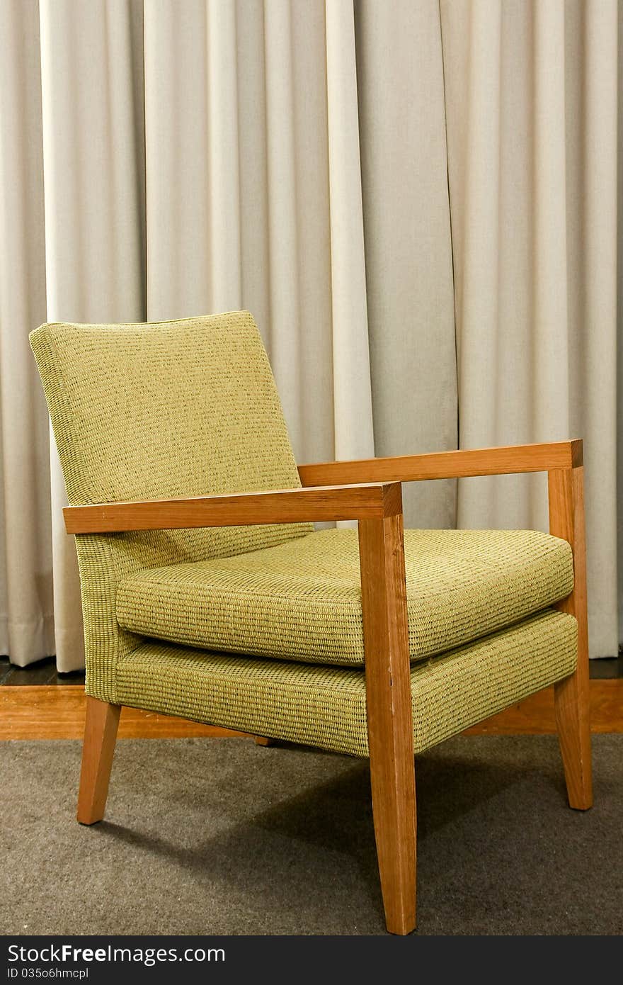 Green wooden and upholstered chair on rug.