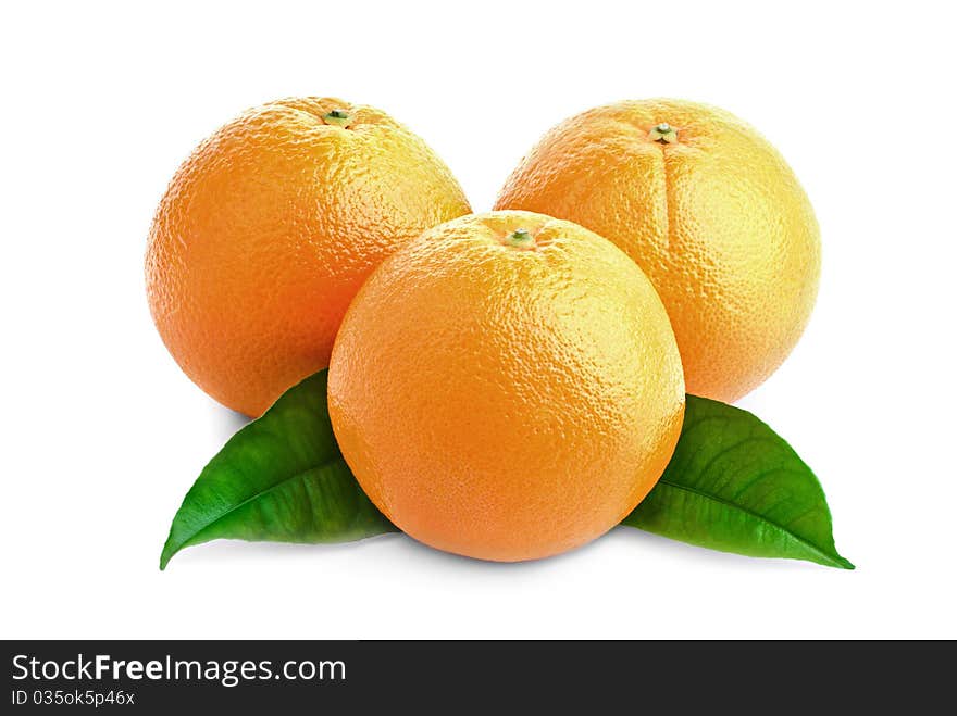 Three juicy oranges and green leaves on a white background. Three juicy oranges and green leaves on a white background