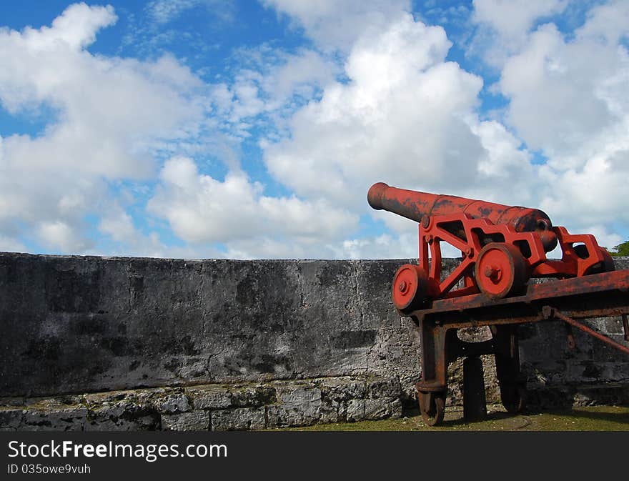 Old war red cannon in a fort directed to the bright blue sky