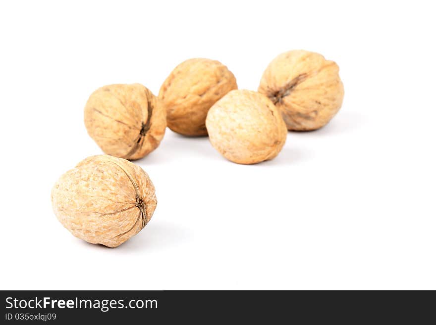 Five walnuts lie on a white background. A shot horizontal, focus on a near nut