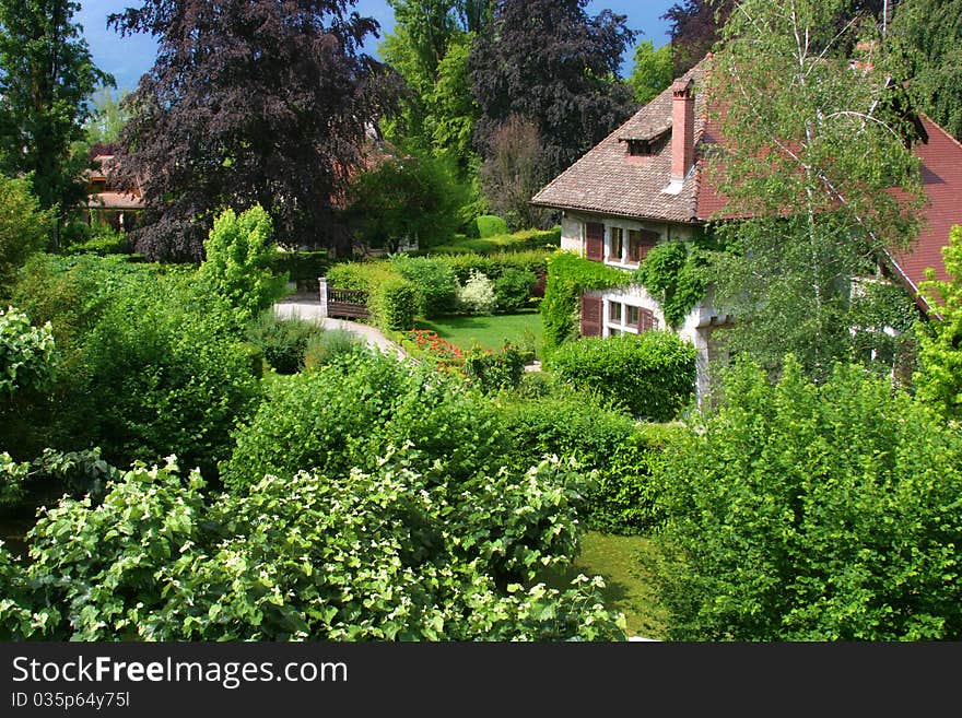 A large old house in France surrounded by a beautiful, lush green garden. A large old house in France surrounded by a beautiful, lush green garden