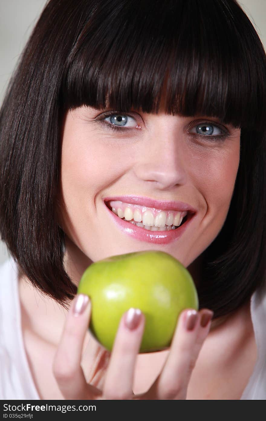 Young woman smiling holding apple. Young woman smiling holding apple