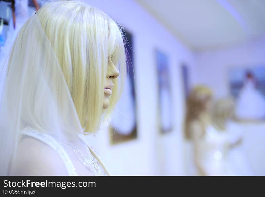 White mannequin in a wedding dress and wig at the shop