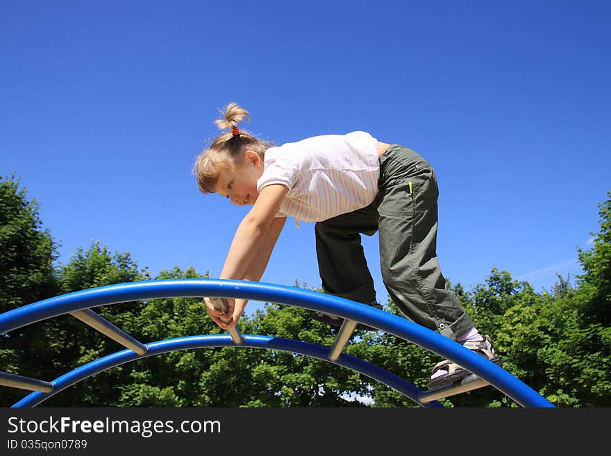 A little girl goes through the ladder at the playground. A little girl goes through the ladder at the playground