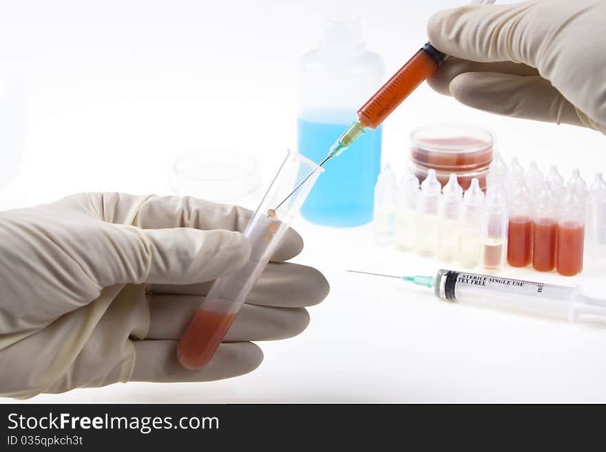 Sampling blood with a syringe and a plastic tube in lab on white background. Sampling blood with a syringe and a plastic tube in lab on white background