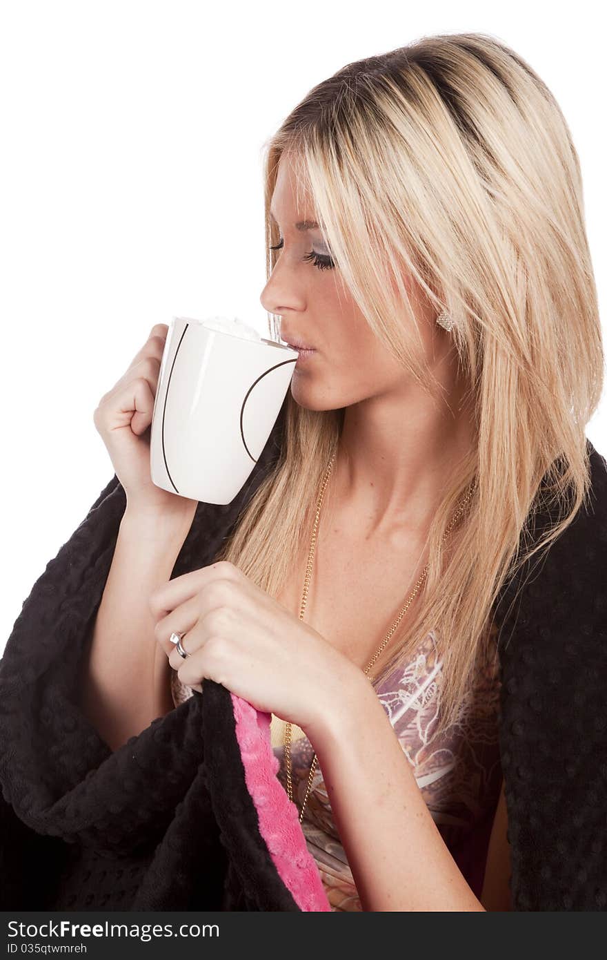 A woman is wrapped in a blanket and sipping from a mug. A woman is wrapped in a blanket and sipping from a mug.