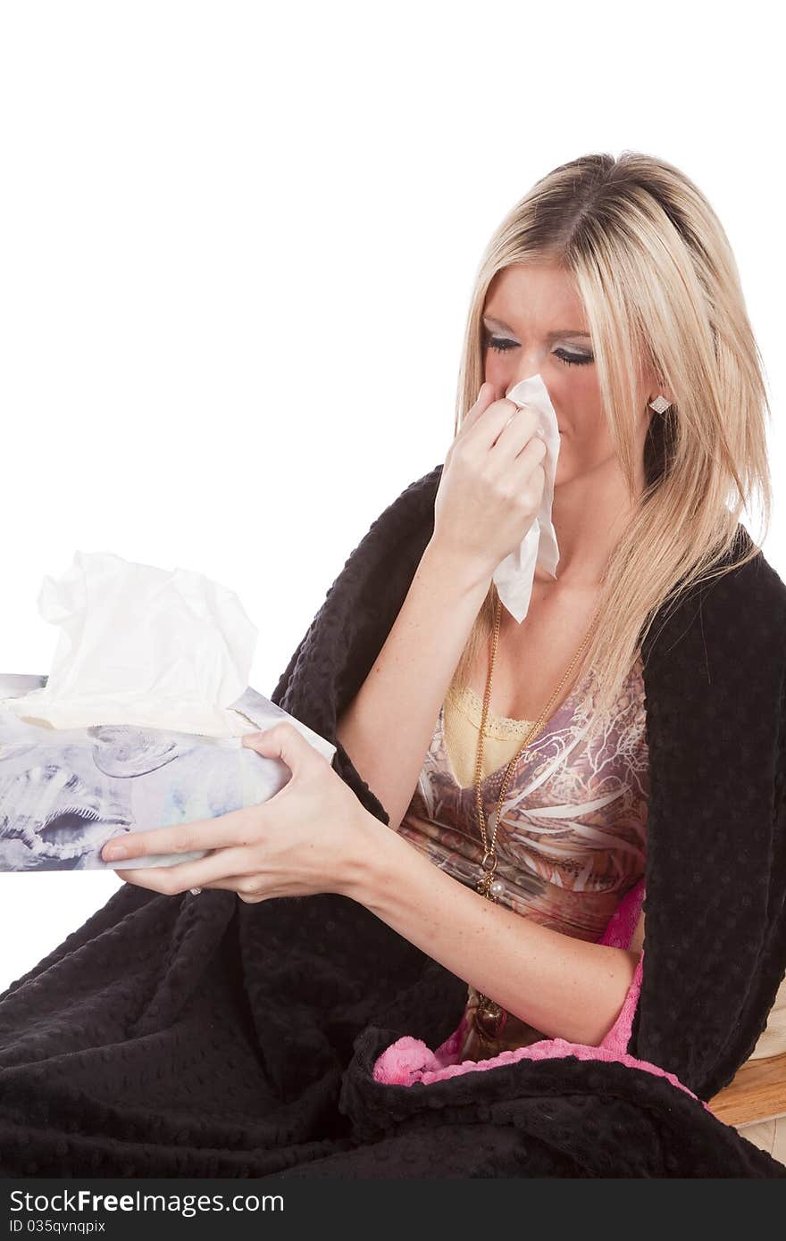 A woman is wrapped in a blanket holding a tissue. A woman is wrapped in a blanket holding a tissue.