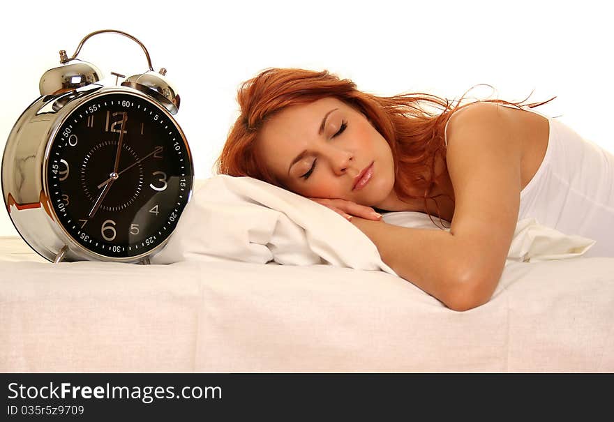 Young woman lying in bed with alarm clock