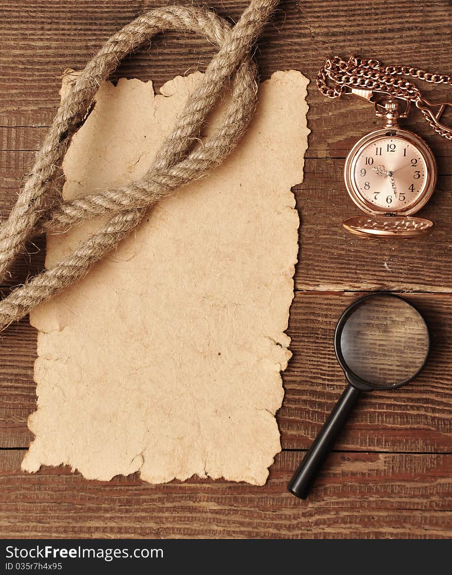 Old paper with pocket watch and magnifying glass on wood background