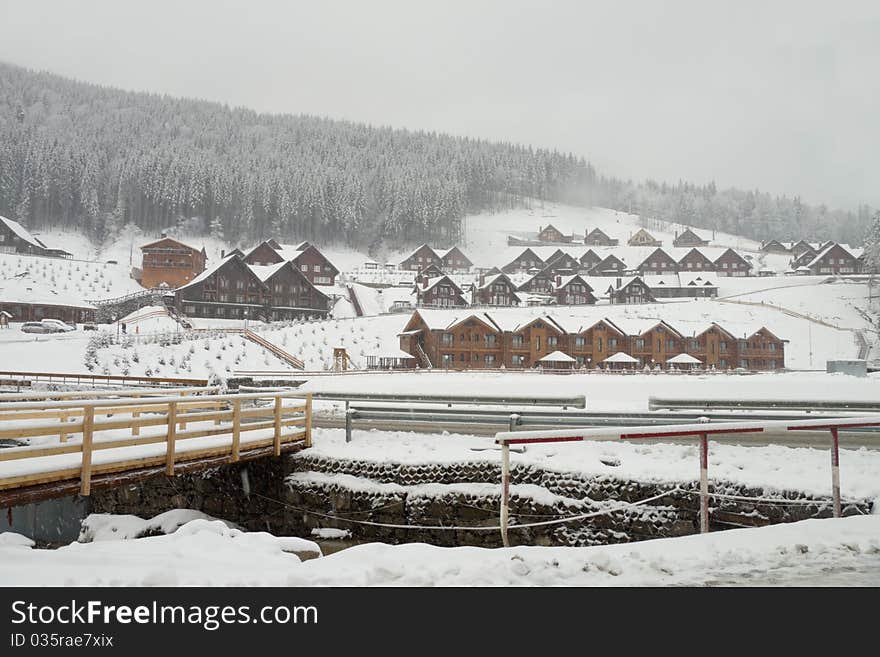 Mountain village on the bank of the river under falling snow. Mountain village on the bank of the river under falling snow