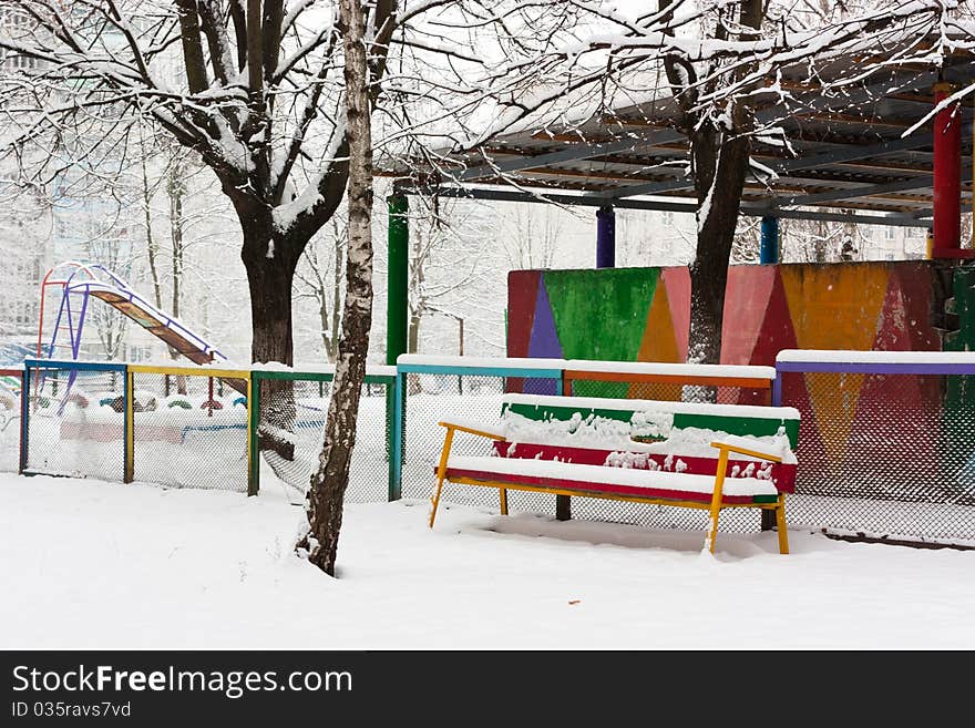Colorful bench in snow in park in winter