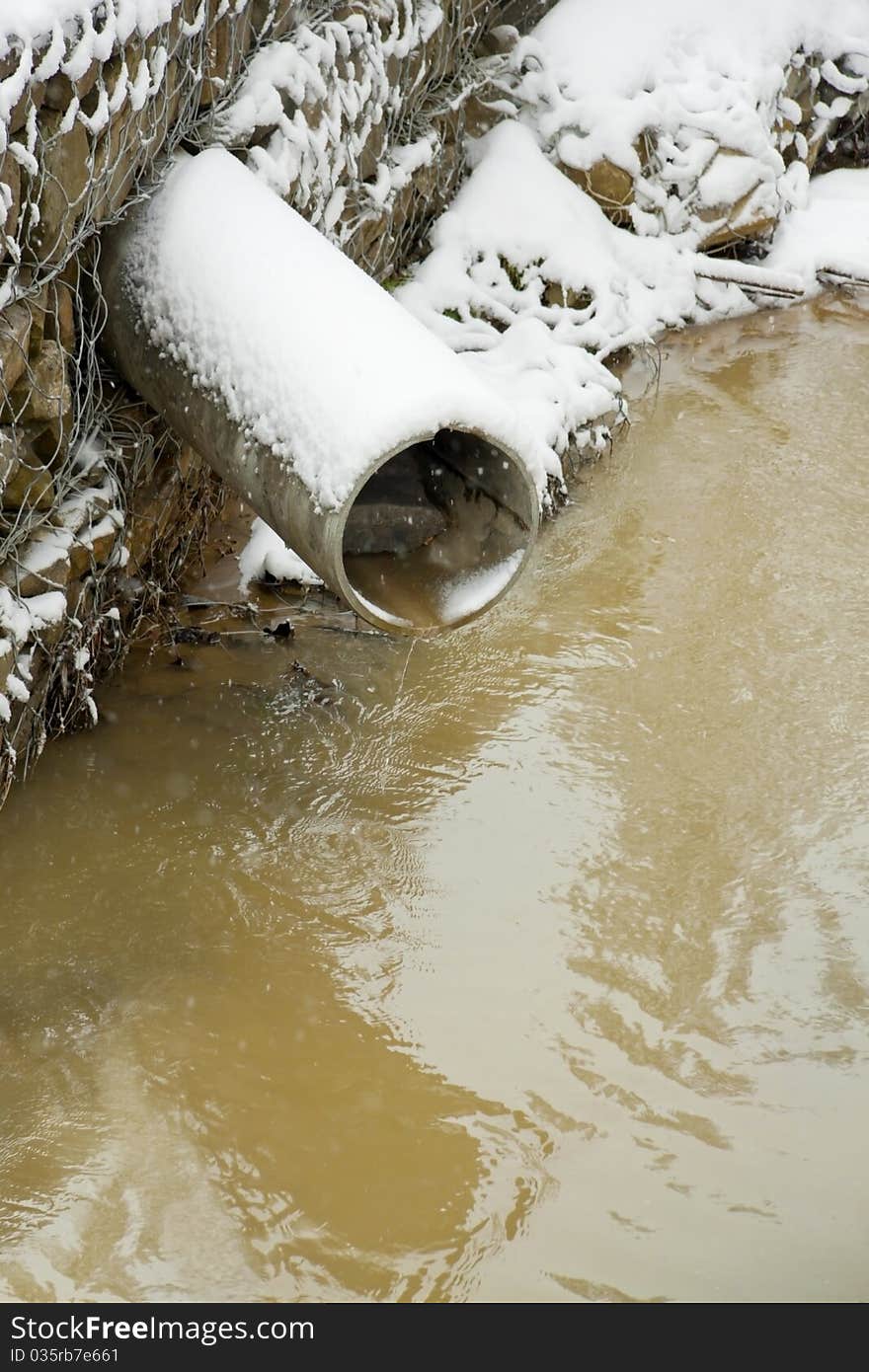 The liquid pours out from a pipe which hangs over water. The liquid pours out from a pipe which hangs over water