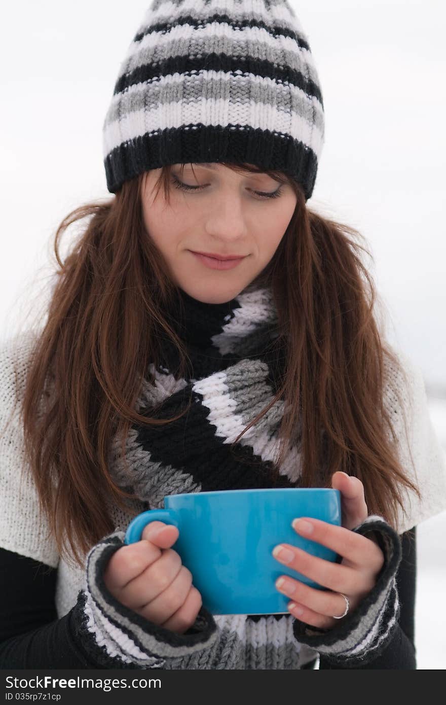 Young beautiful sad girl holding a big blue cup. Young beautiful sad girl holding a big blue cup