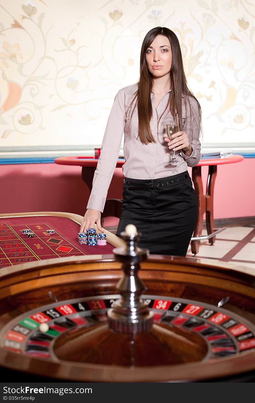 Beautiful young lady with wineglass stay near roulette table. Beautiful young lady with wineglass stay near roulette table