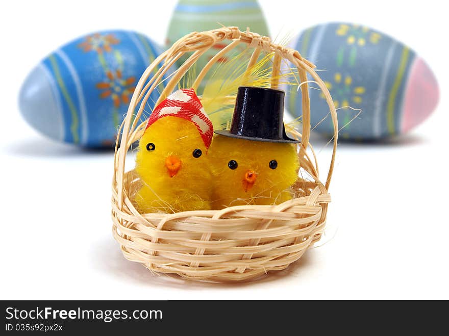 A couple of chicks in a basket with some eggs in the background. A couple of chicks in a basket with some eggs in the background.