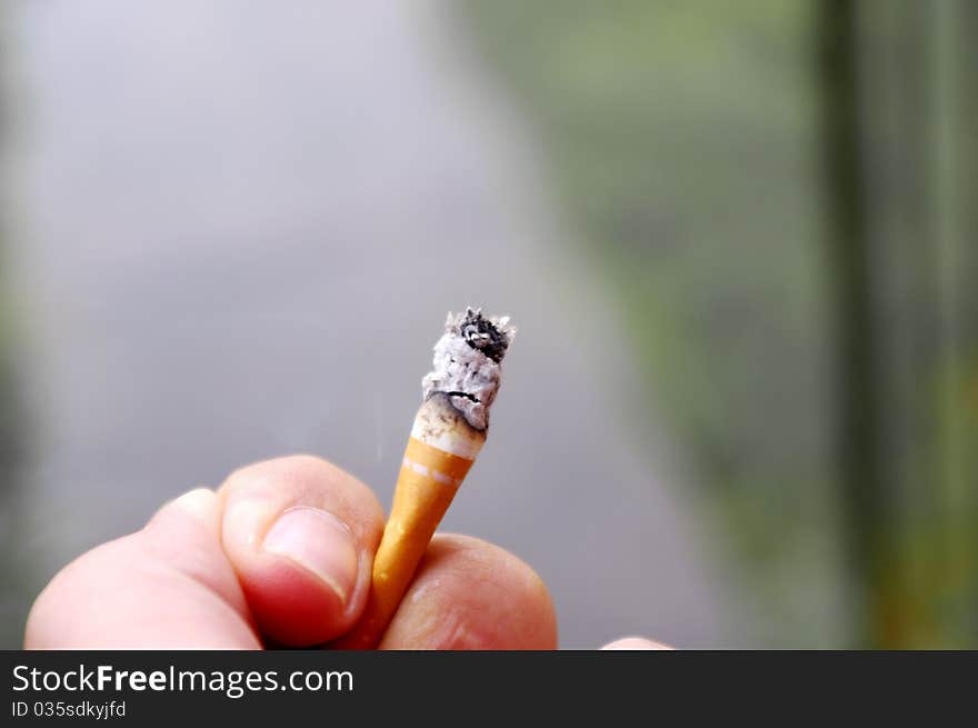 Close-up of hand holding cigarette butt