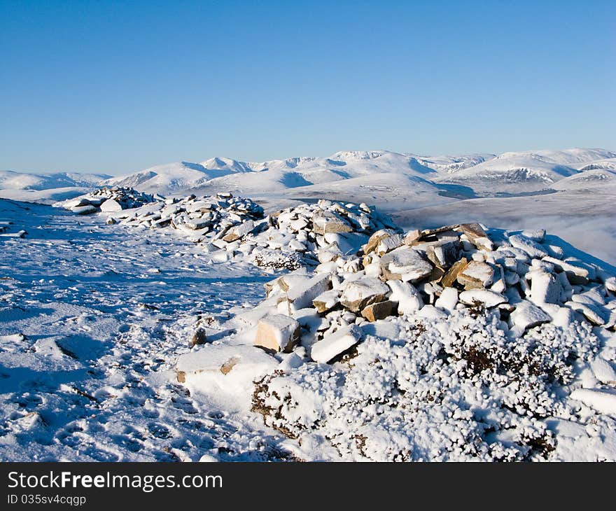 Distant view of Cairngorm mountains in winter over rocky foreground. Distant view of Cairngorm mountains in winter over rocky foreground