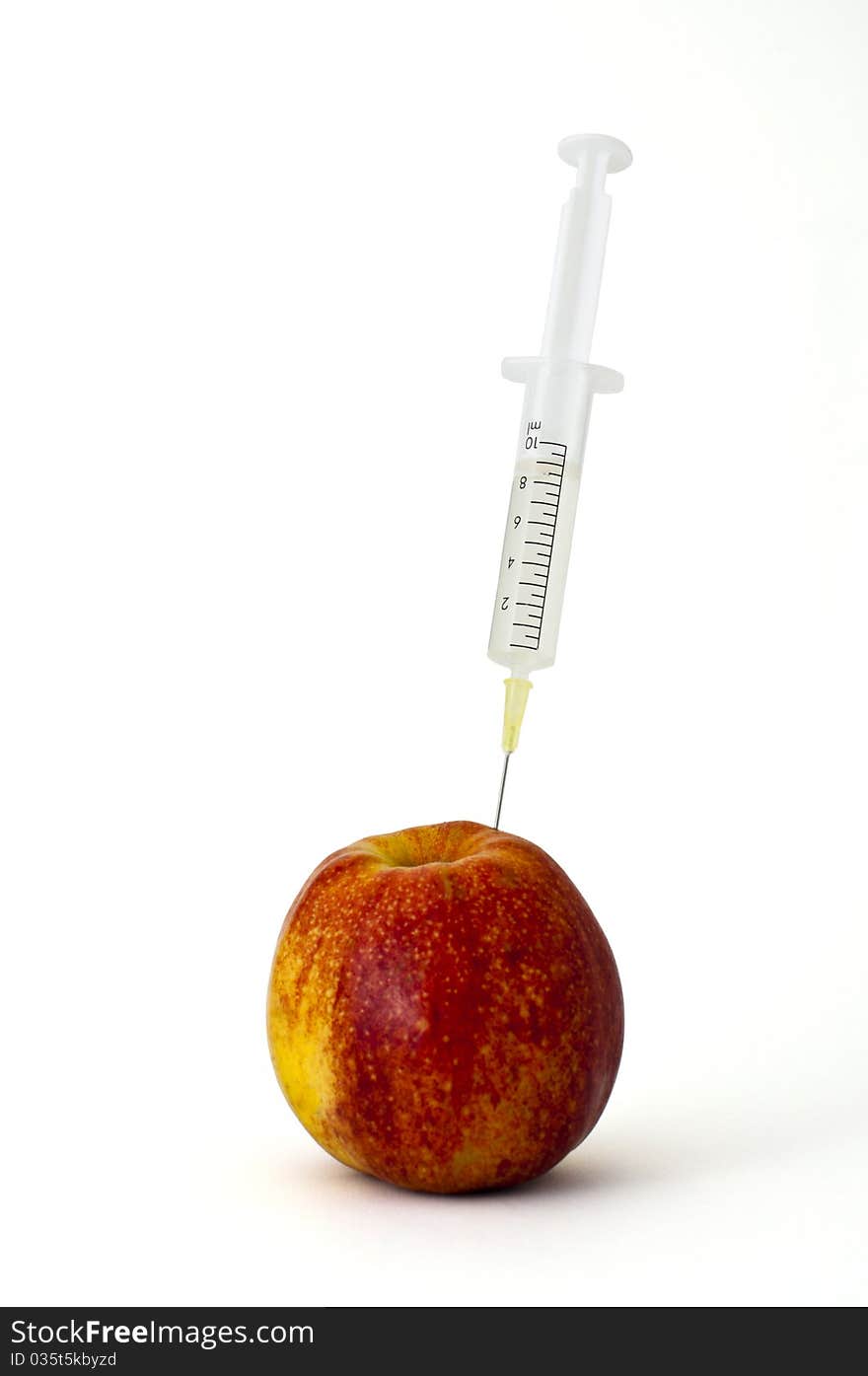 Syringe stuck into an apple on white background