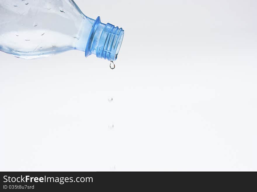 Water dripping from a plastic bottle on white background. Water dripping from a plastic bottle on white background