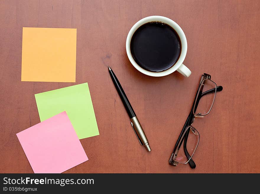 Reminder notes, pen and glasses with cup of coffee