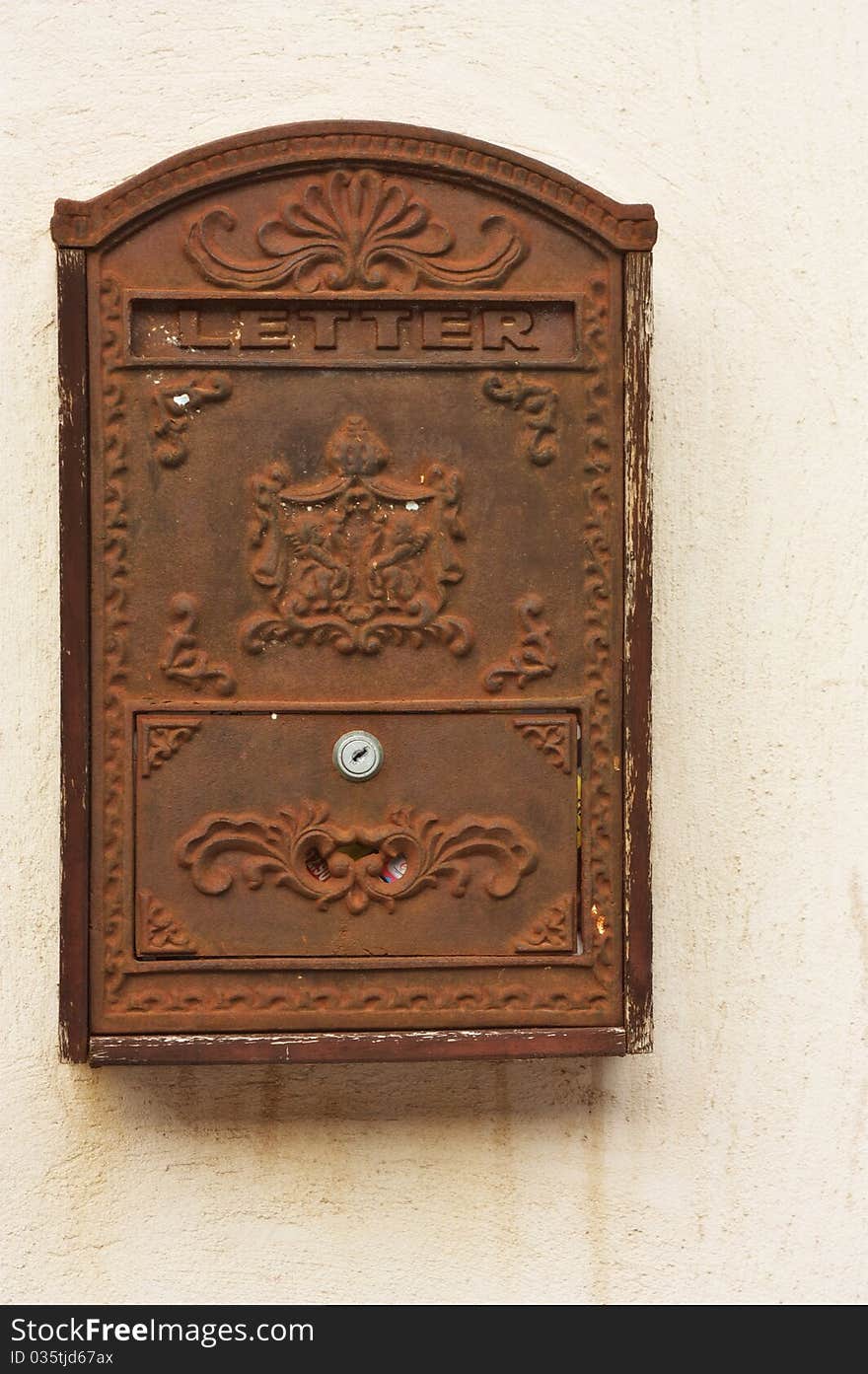 An image of an antique metal and rusty mail box on a wall. An image of an antique metal and rusty mail box on a wall