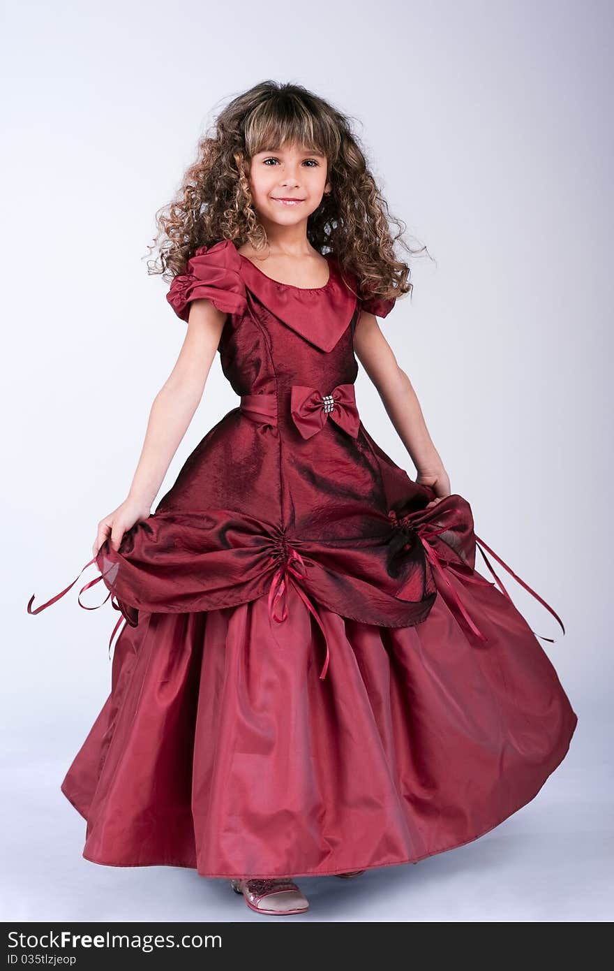 Beautiful little girl dancing in wine red dress