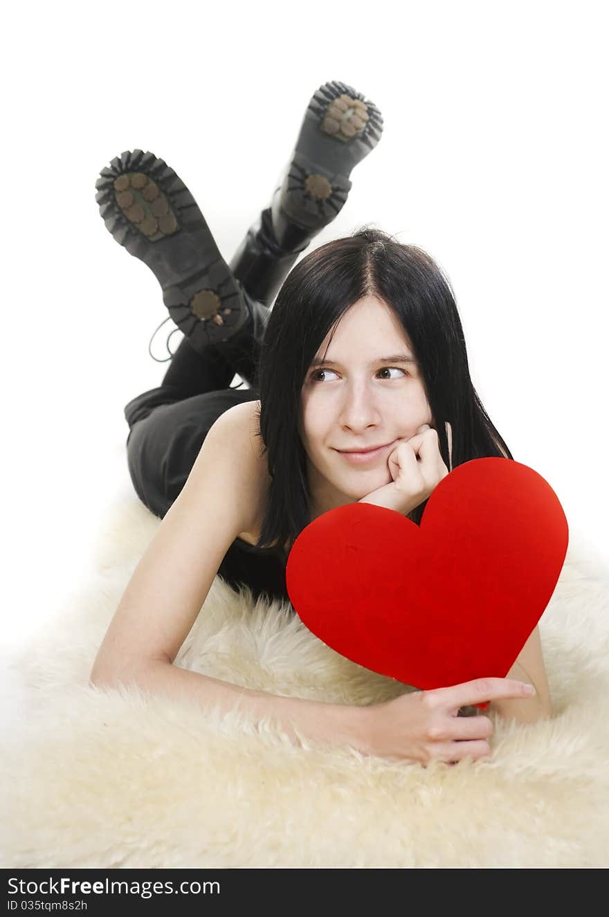 Positive young goth female lies with red heart in hands. Positive young goth female lies with red heart in hands