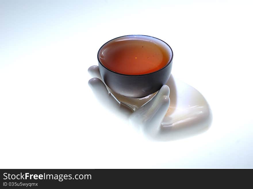 A teacup with tea on a hand-shape sculpture.