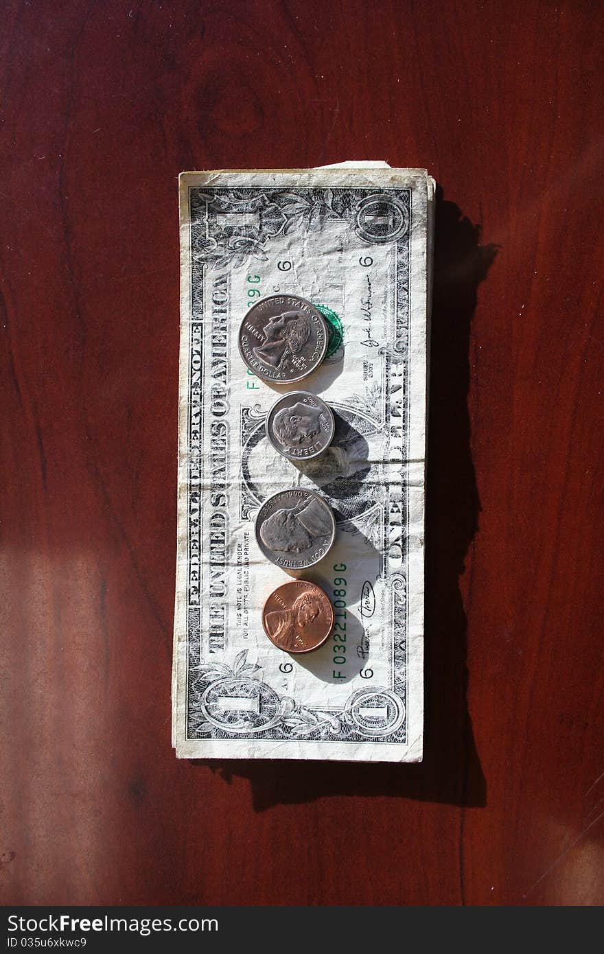 Stack of dollars with coins laid out on top. Stack of dollars with coins laid out on top.