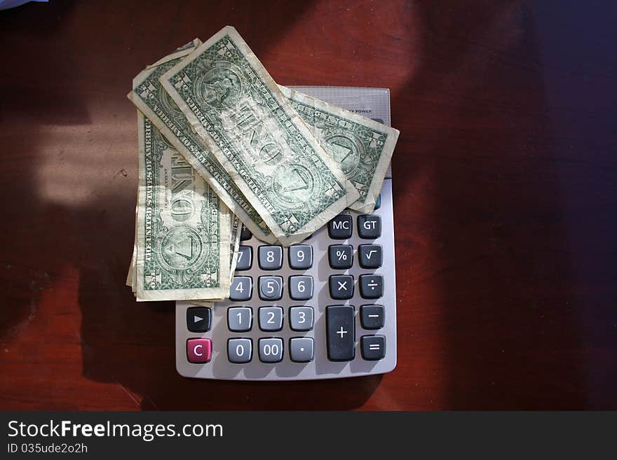 Dollar bills set on top of a calculator. Dollar bills set on top of a calculator.