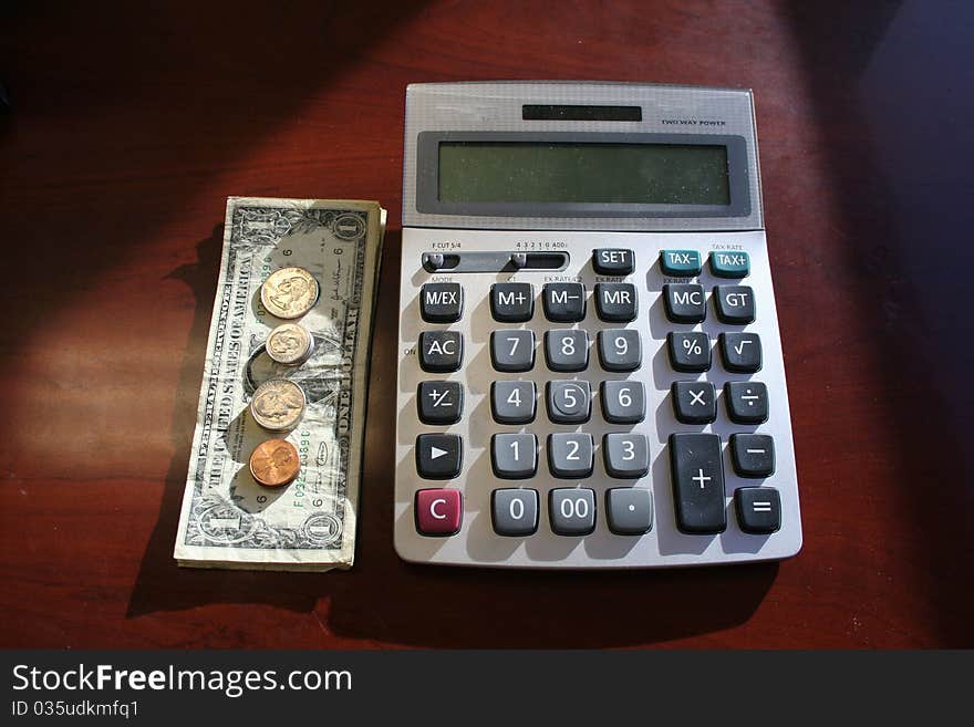 Calculator with dollar bills and coins set next to it. Calculator with dollar bills and coins set next to it.